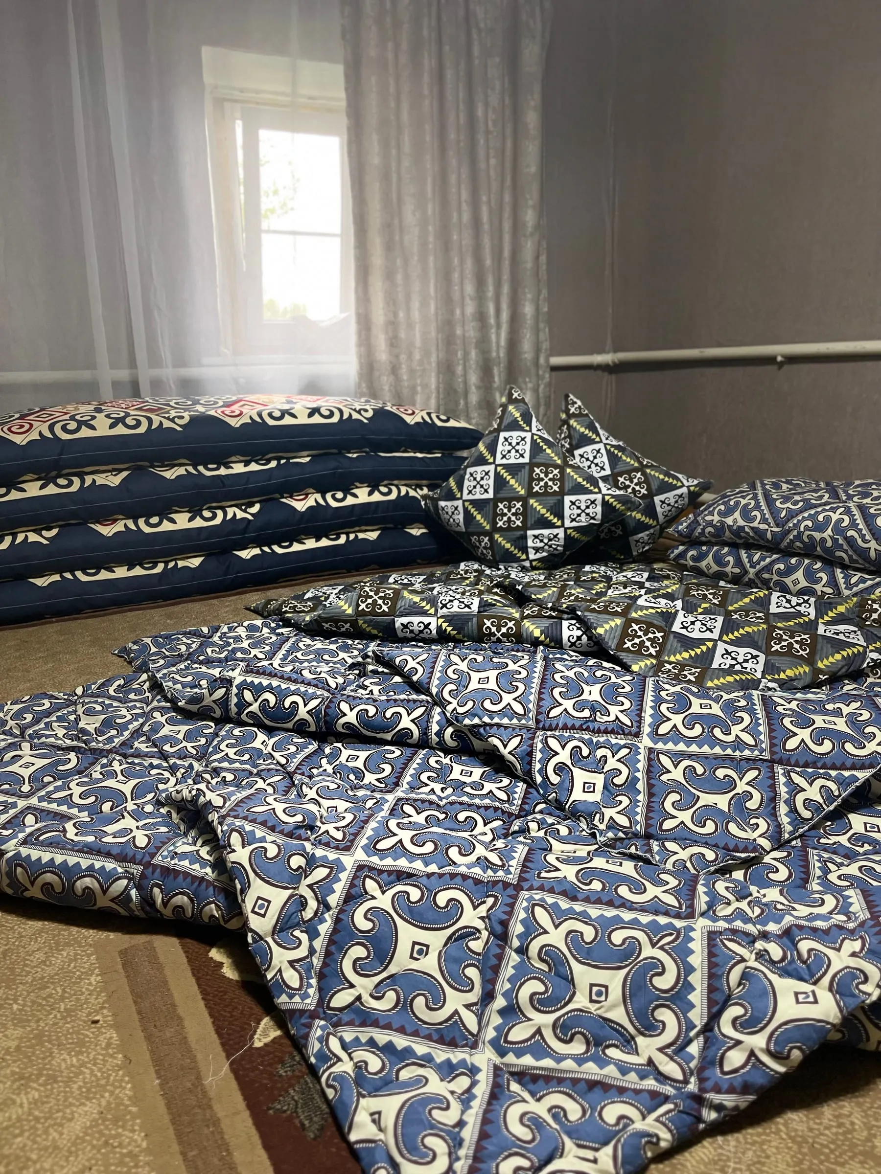 Стёганые одеяла с сине-белым орнаментом, разложенные на полу